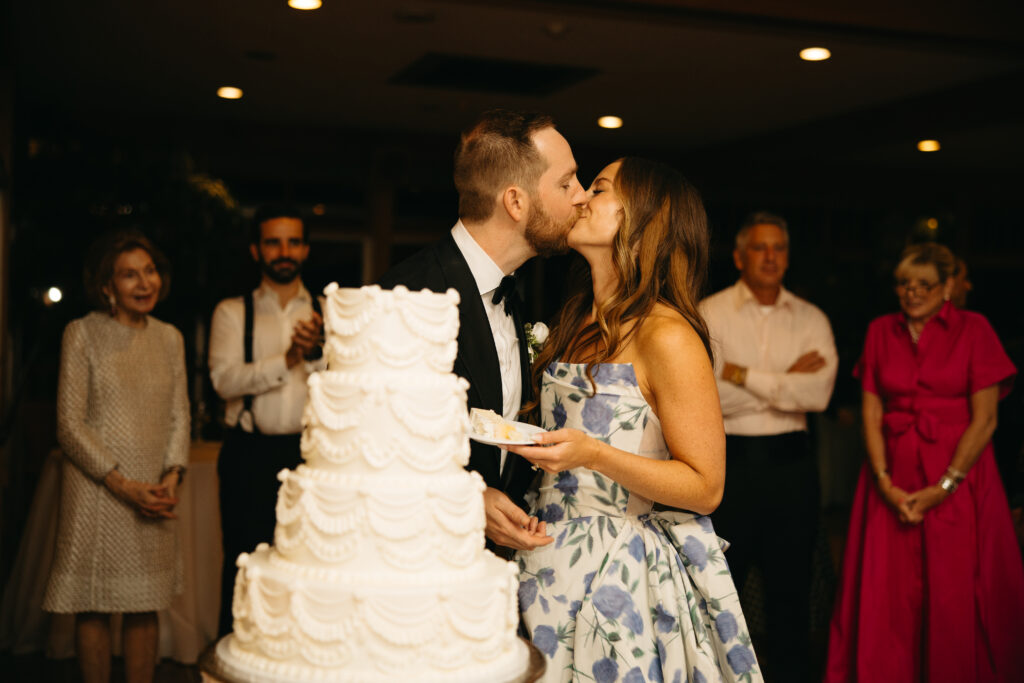 bride and groom kissing standing behind wedding cake