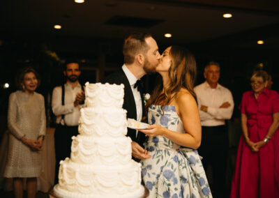 bride and groom kissing standing behind wedding cake