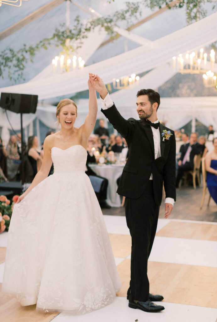 bride and groom dancing on birch and white check dance floor under clear wedding tent