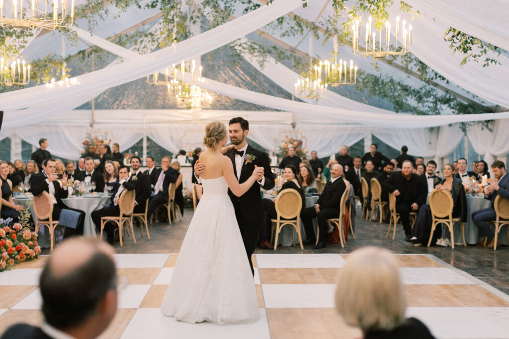 bride and groom dancing on birch and white check dance floor under clear wedding tent