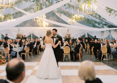 bride and groom dancing on birch and white check dance floor under clear wedding tent