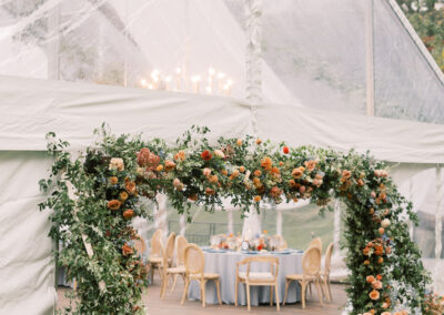 clear top wedding tent with floral archway framing the tent entrance