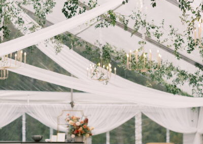 clear top wedding tent with ceiling draping, natural wood chairs, blue table linens