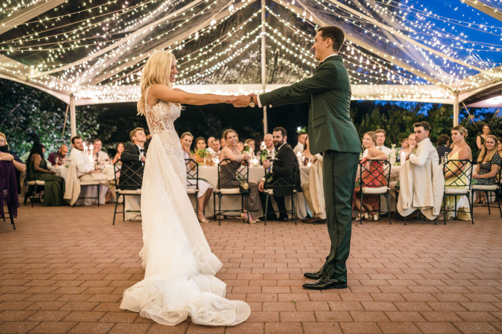 bride and groom dancing under clear top tent with twinkle lighting