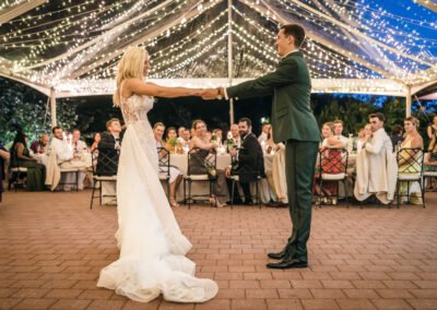 bride and groom dancing under clear top tent with twinkle lighting