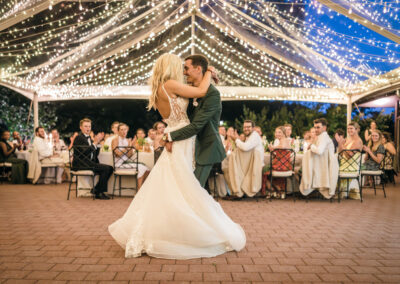 bride and groom dancing under clear top tent with twinkle lighting