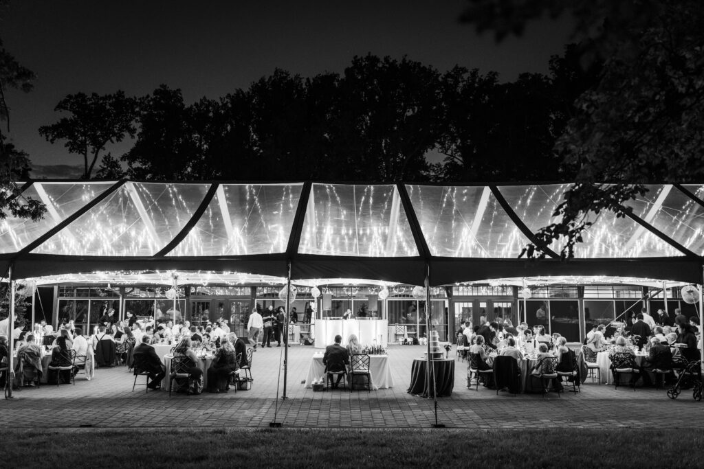 black and white photo of clear top wedding tent photo with twinkle lights glowing thru the tent top