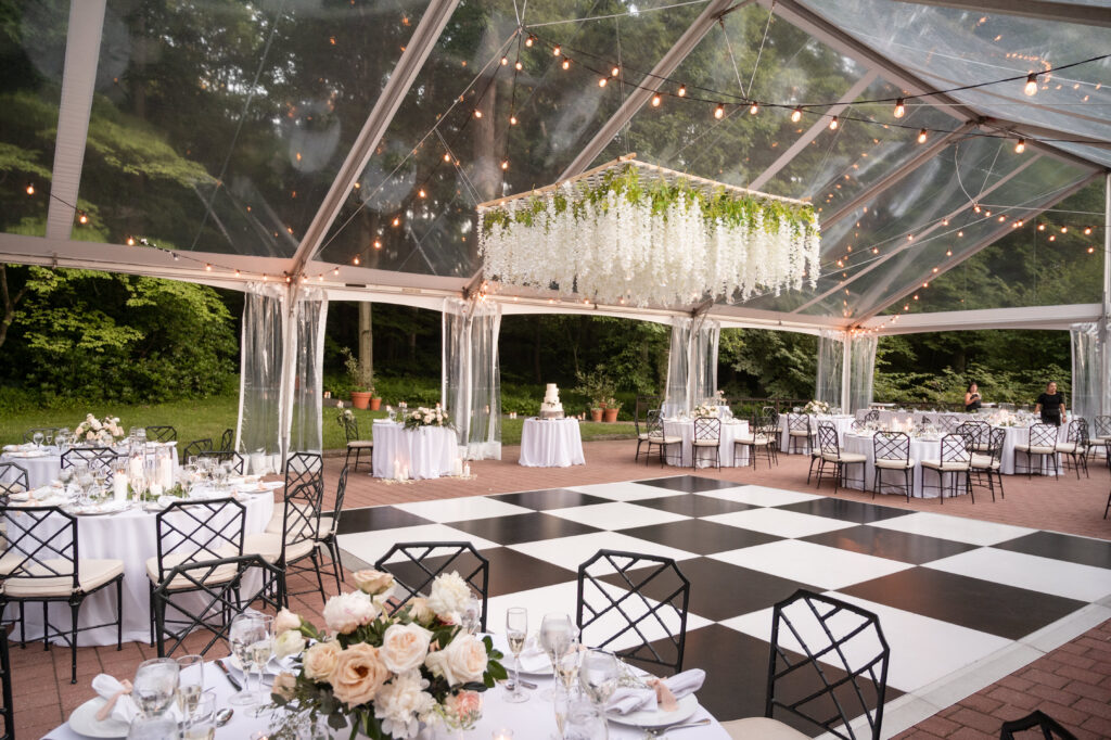 clear top wedding tent with floral chandelier and bold black and white dance floor
