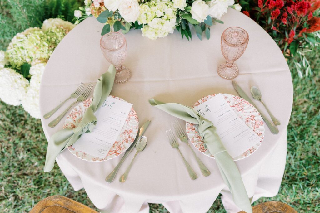 table setting with blush pink etched water goblets and floral print plates on cream table linen