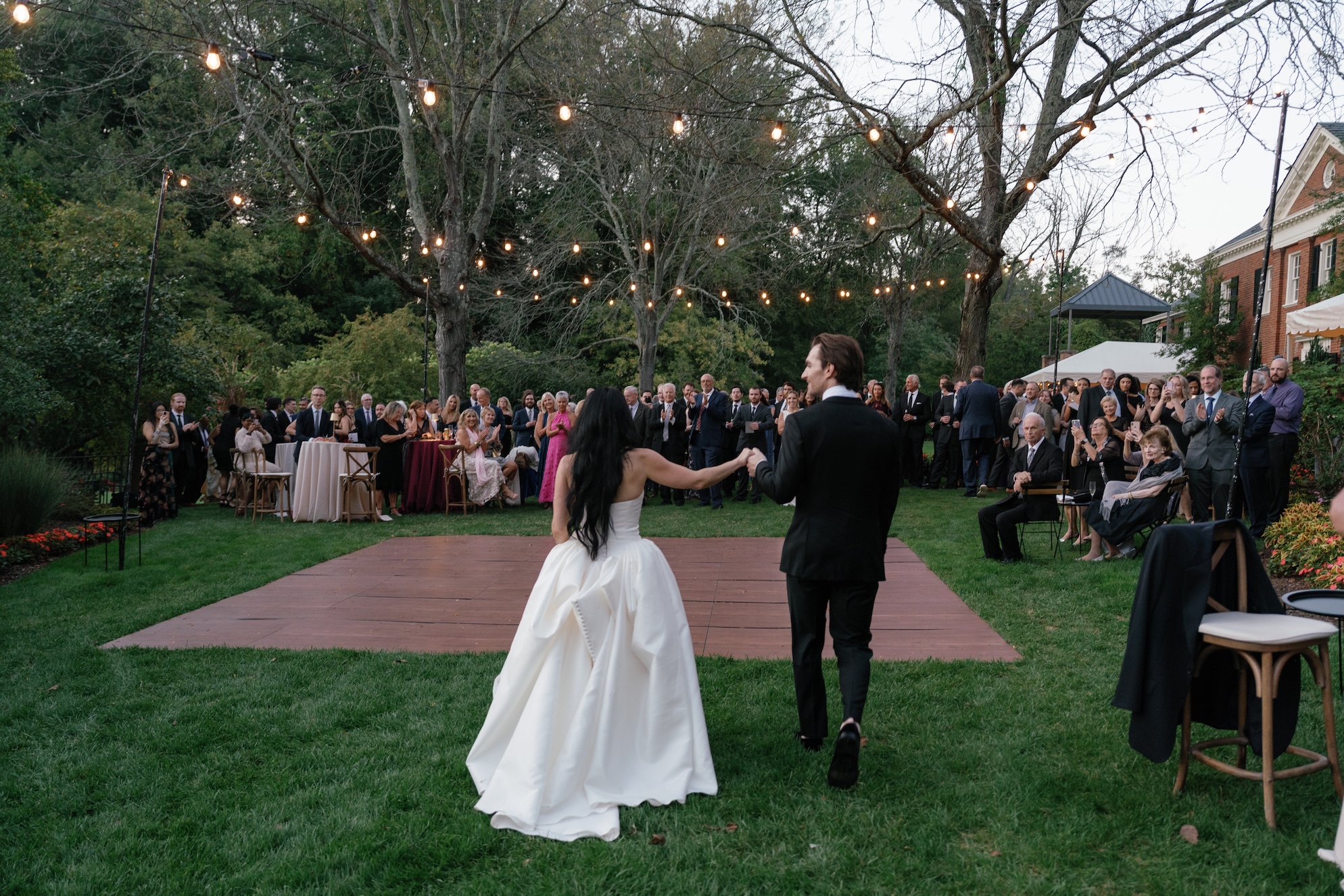 Bride and Groom walking towards an al fresco dance floor installation by Collective Event Group