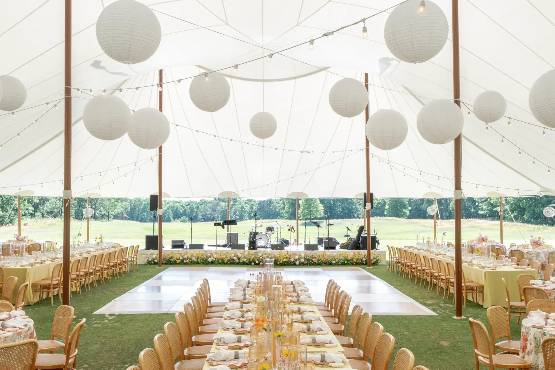 Interior of a sailcloth tent installation at Hidden Creek Golf Club in the summer of 2026 by Collective Event Group, with paper lanterns hanging from the ceiling