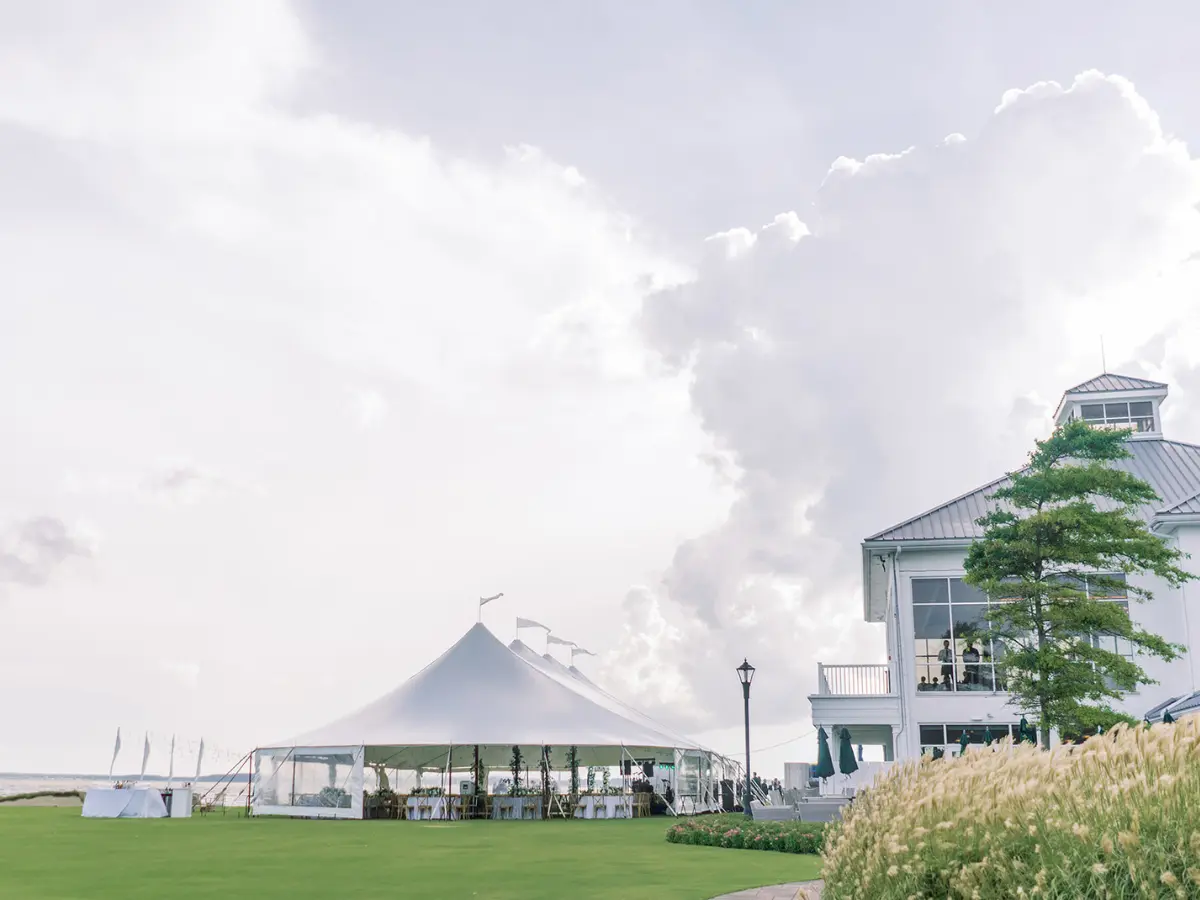 A view of a sailcoth tent on the lawn for a summer event
